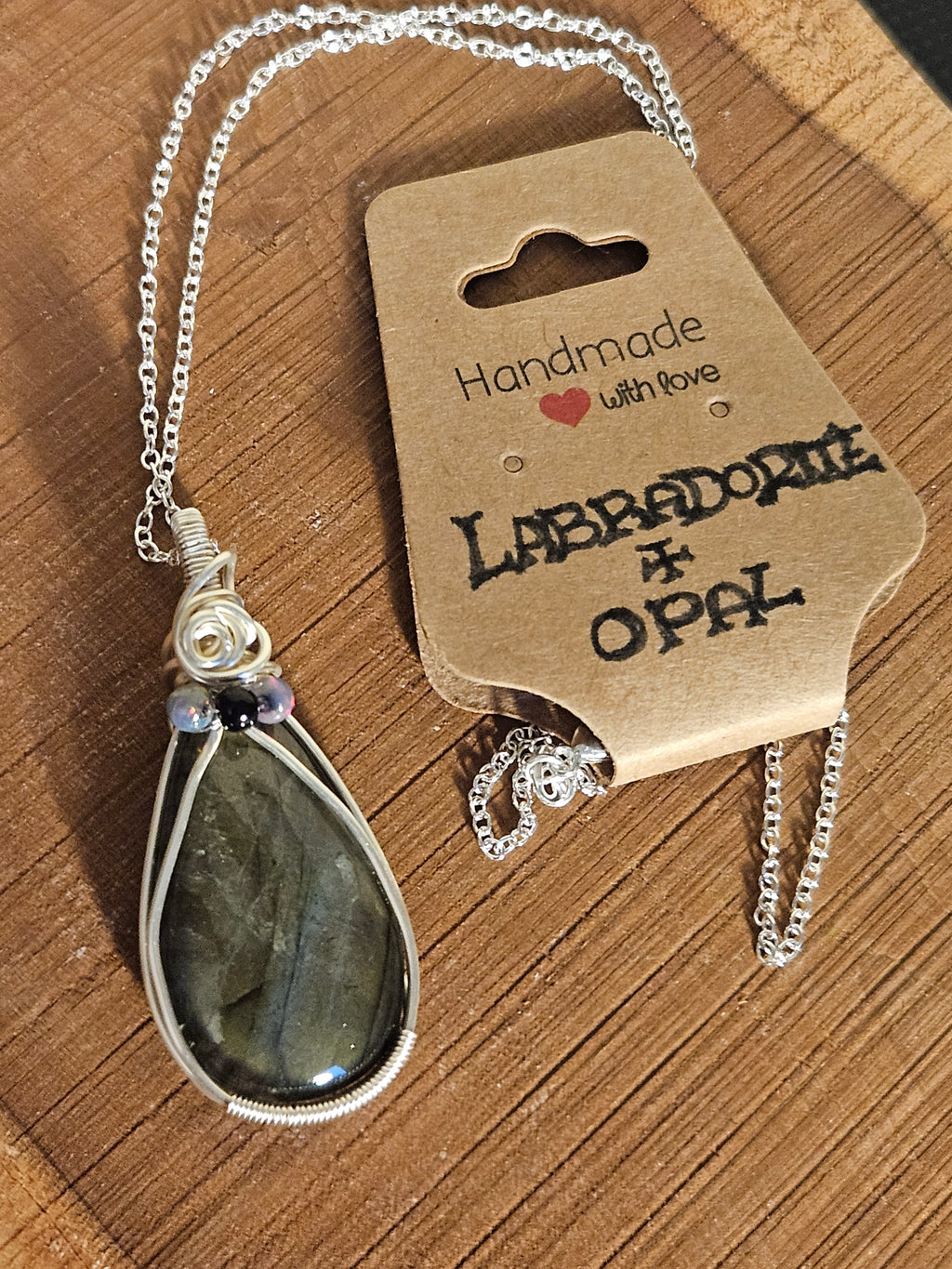 Labradorite opal necklace on a wooden surface with a branded card.