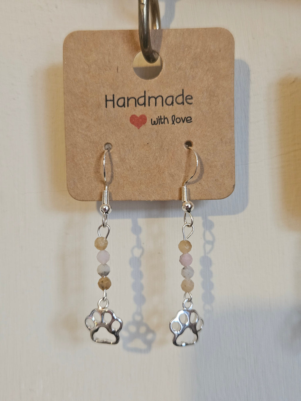Pair of earrings with paw prints on a 'Handmade with Love' card.
