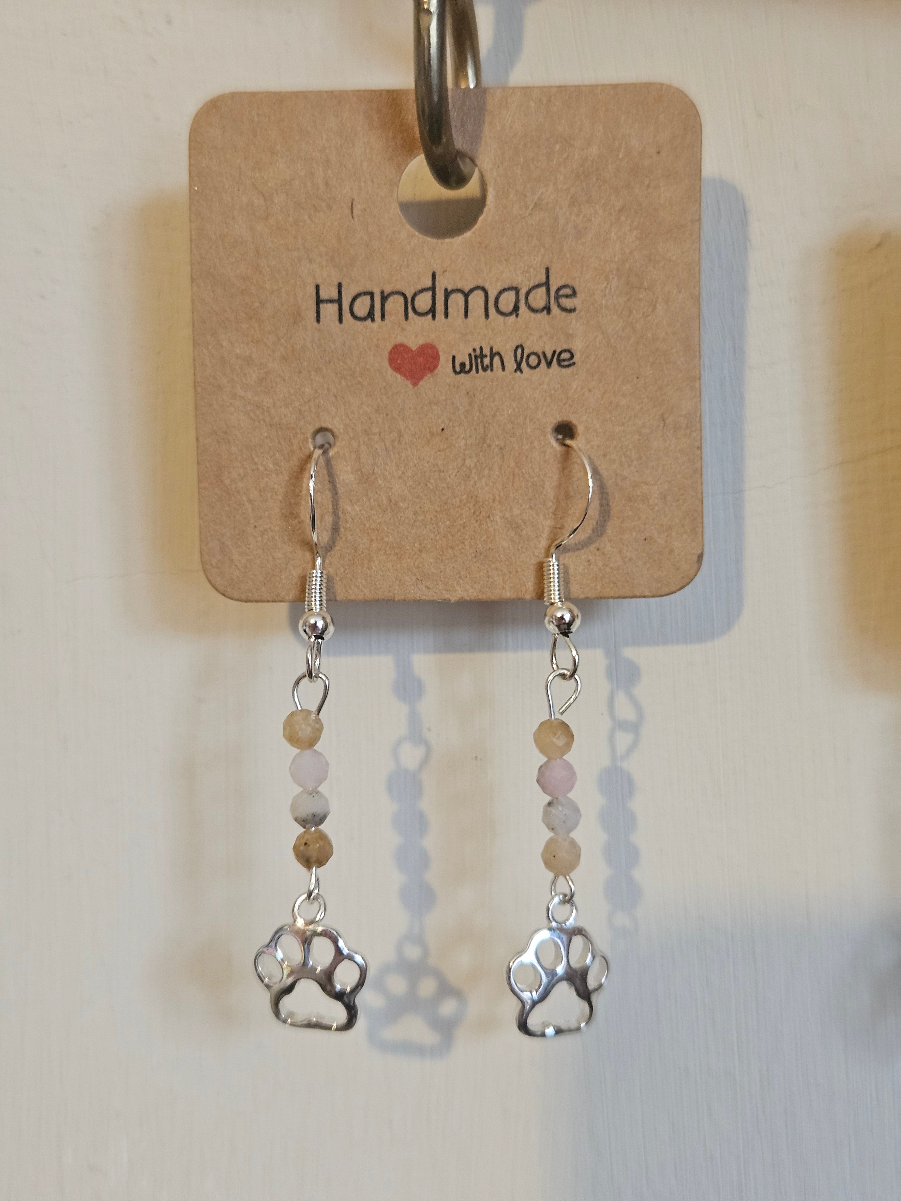 Pair of earrings with paw prints on a 'Handmade with Love' card.