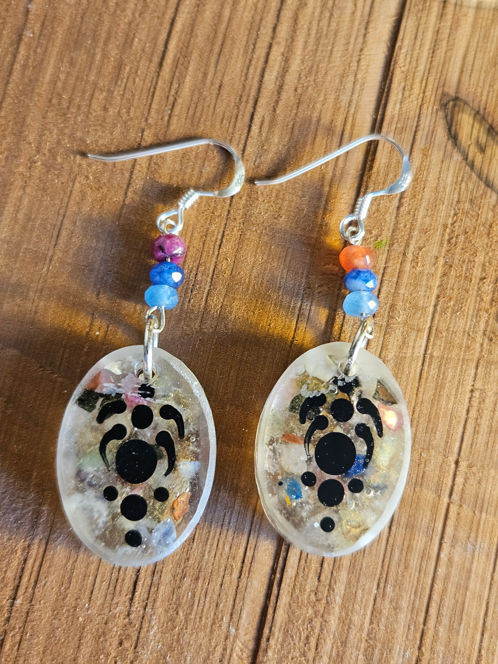 Pair of earrings with decorative stones and beads on a wooden surface