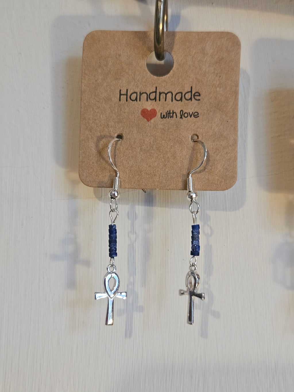 Silver earrings with blue beads on a 'handmade with love' card.