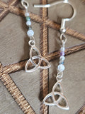 Silver Celtic knot earrings with beaded chain on a wooden surface