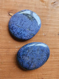 Two Dumortierite smoothstones on a wooden surface