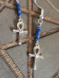 Silver ankh pendants with blue beads on a textured surface