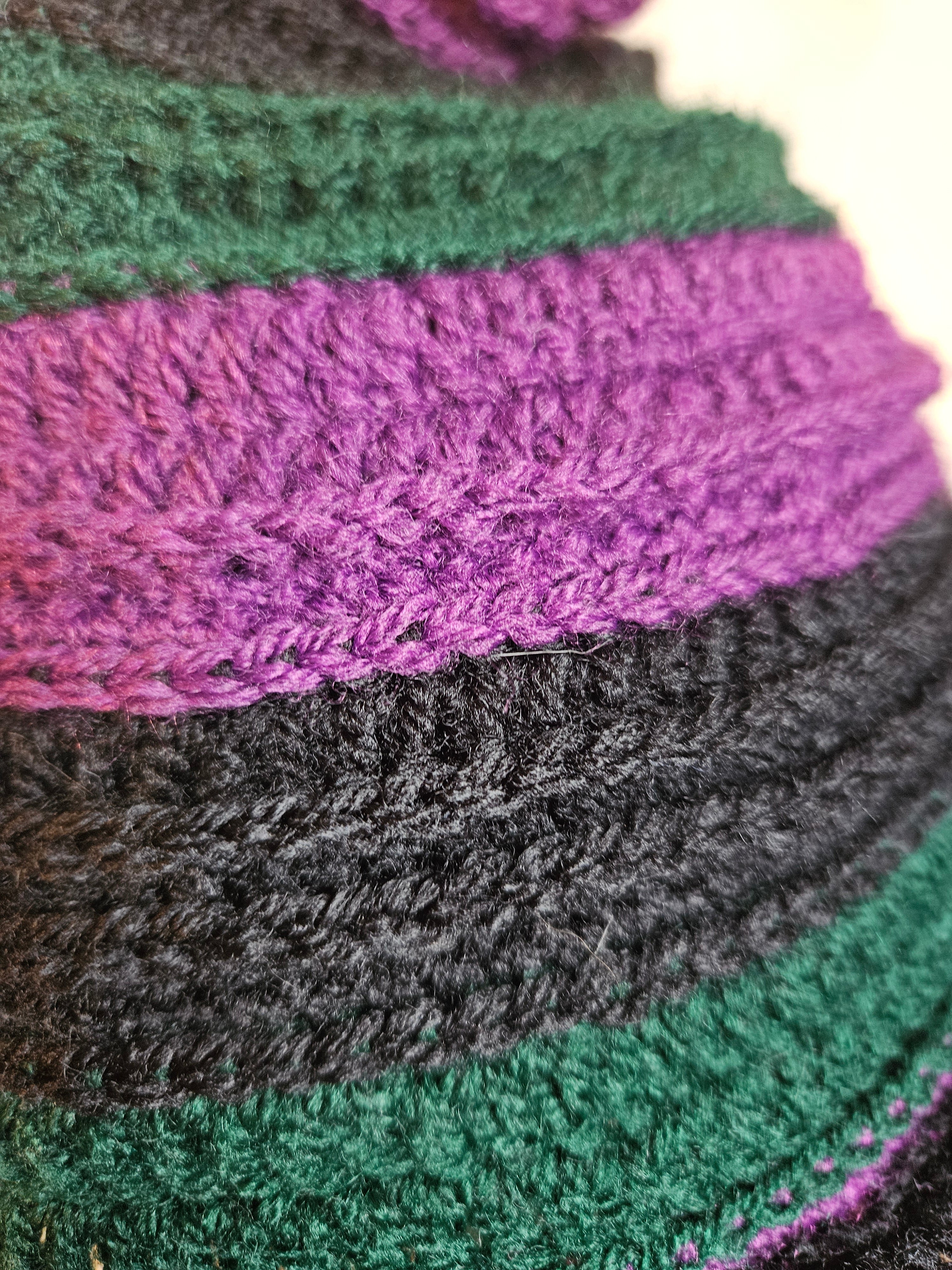 Close-up of a crochet with purple, black, and green colors.