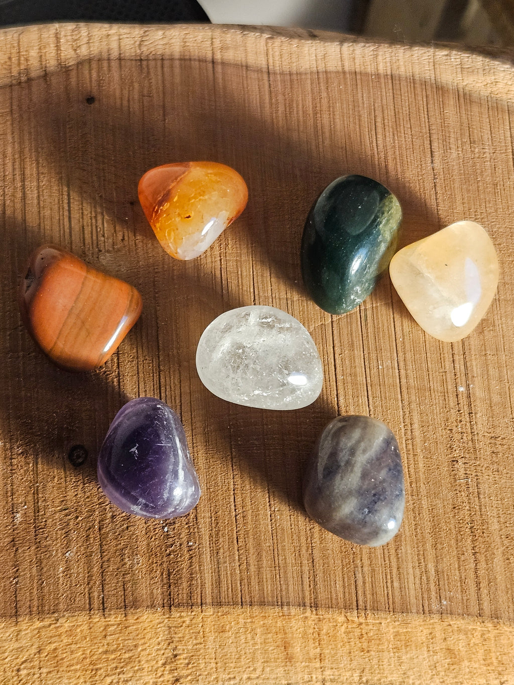 Set of chakra tumble stones on a wooden board
