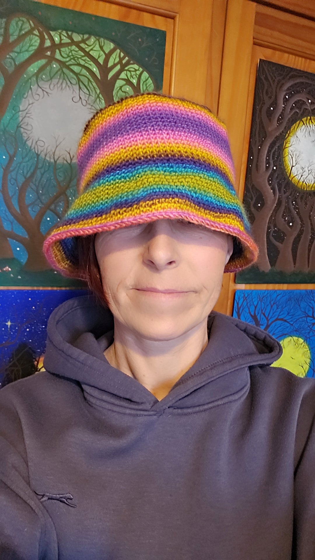 Person wearing a colorful striped hat indoors with decorative wall art in the background