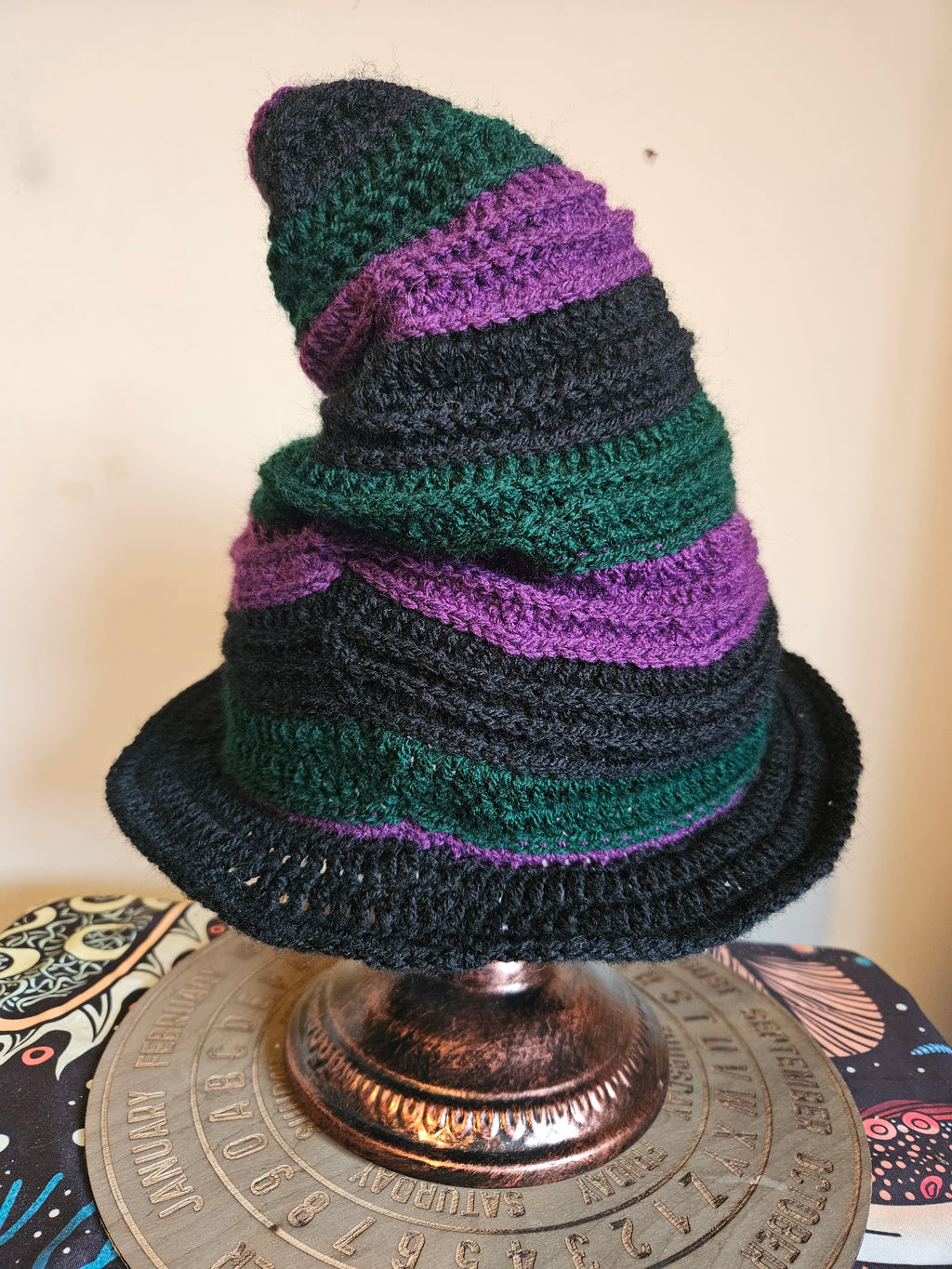 Crocheted hat with purple and green pattern on a metallic object