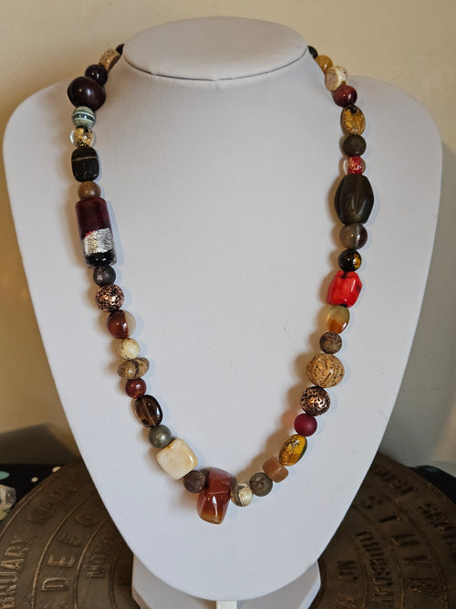 Beaded necklace on a white mannequin bust with a textured surface background