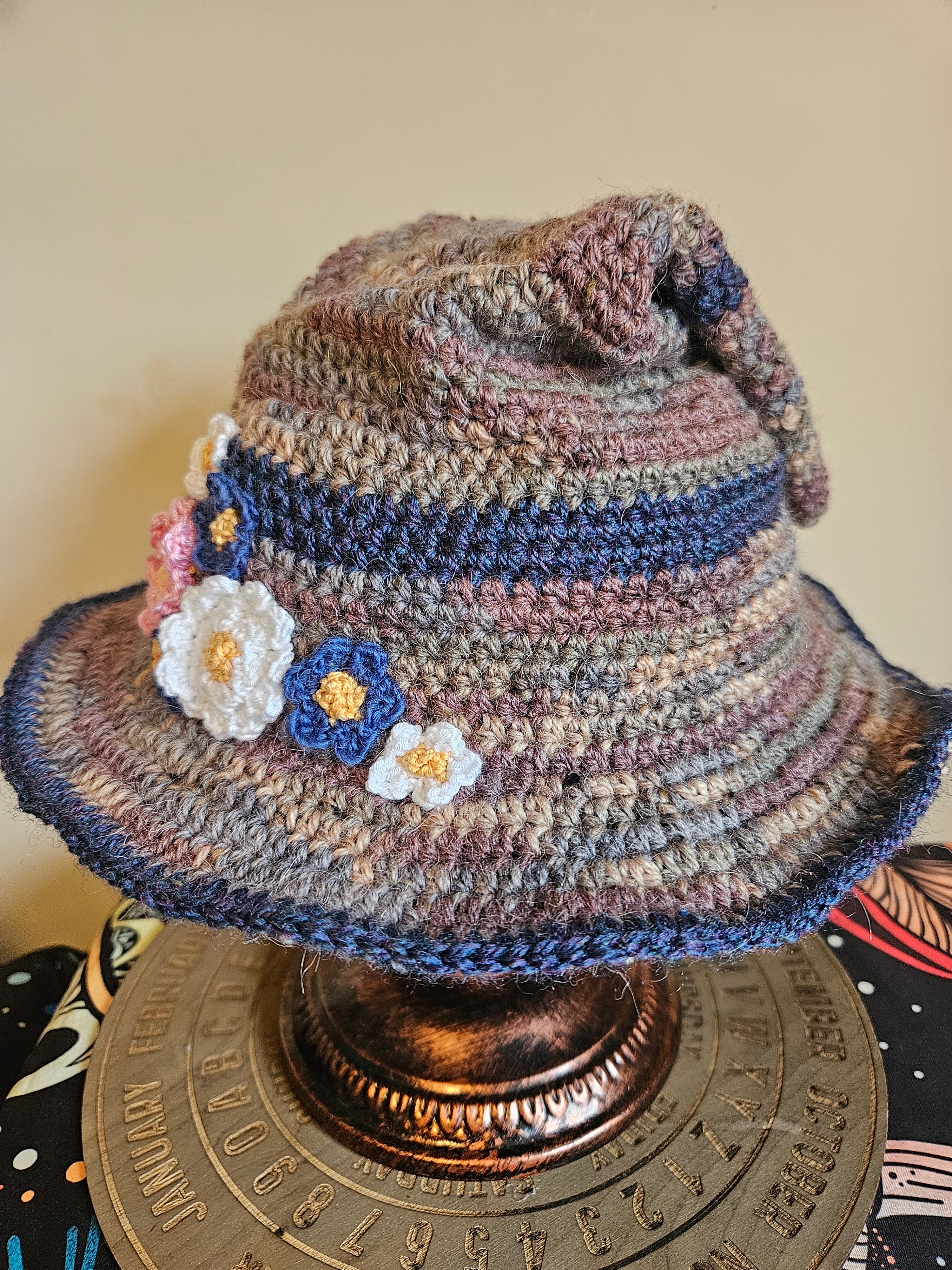 Crocheted hat with floral decorations on a textured surface