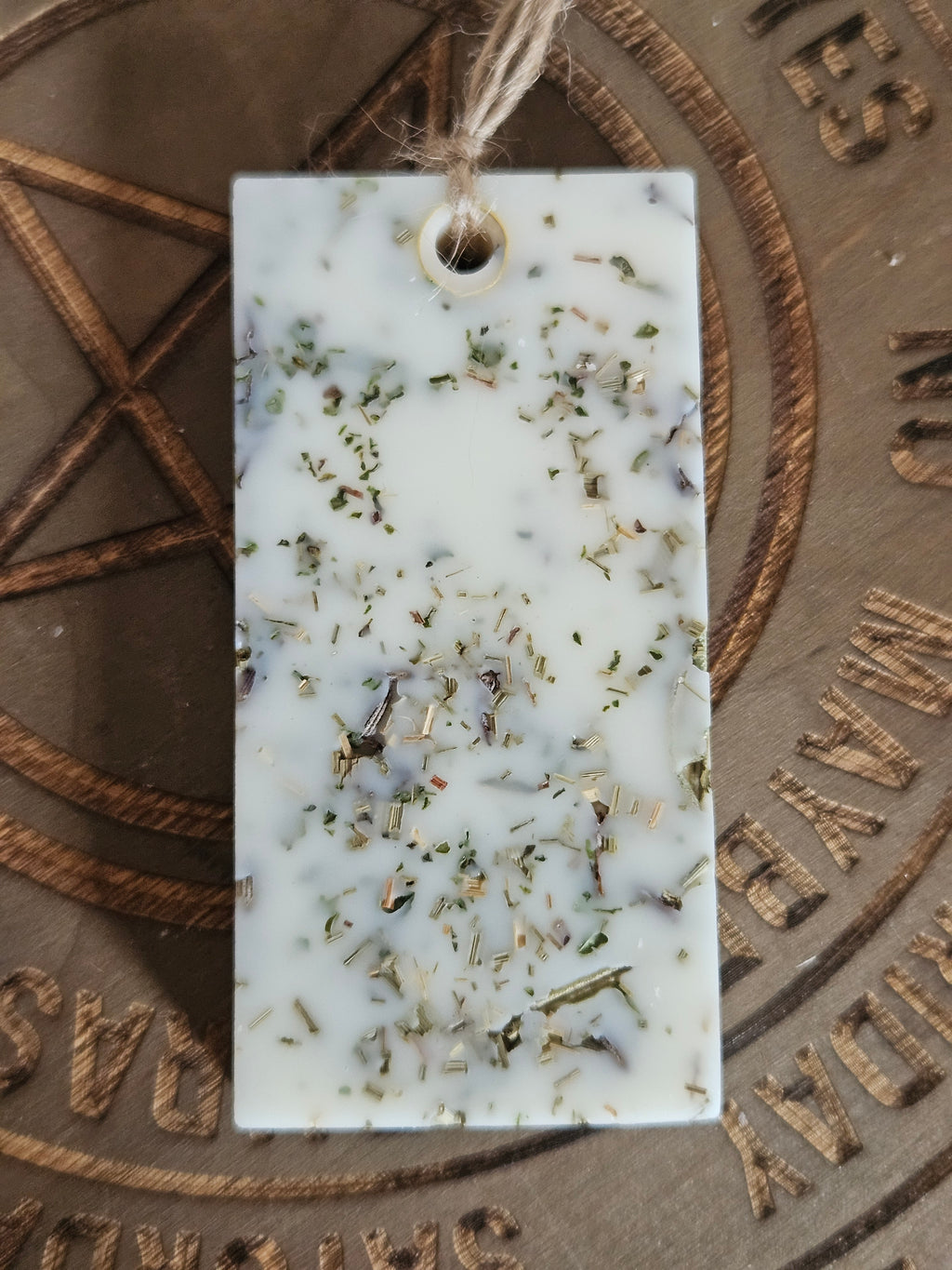 Rectangular scented pendant with natural ingredients on a textured surface