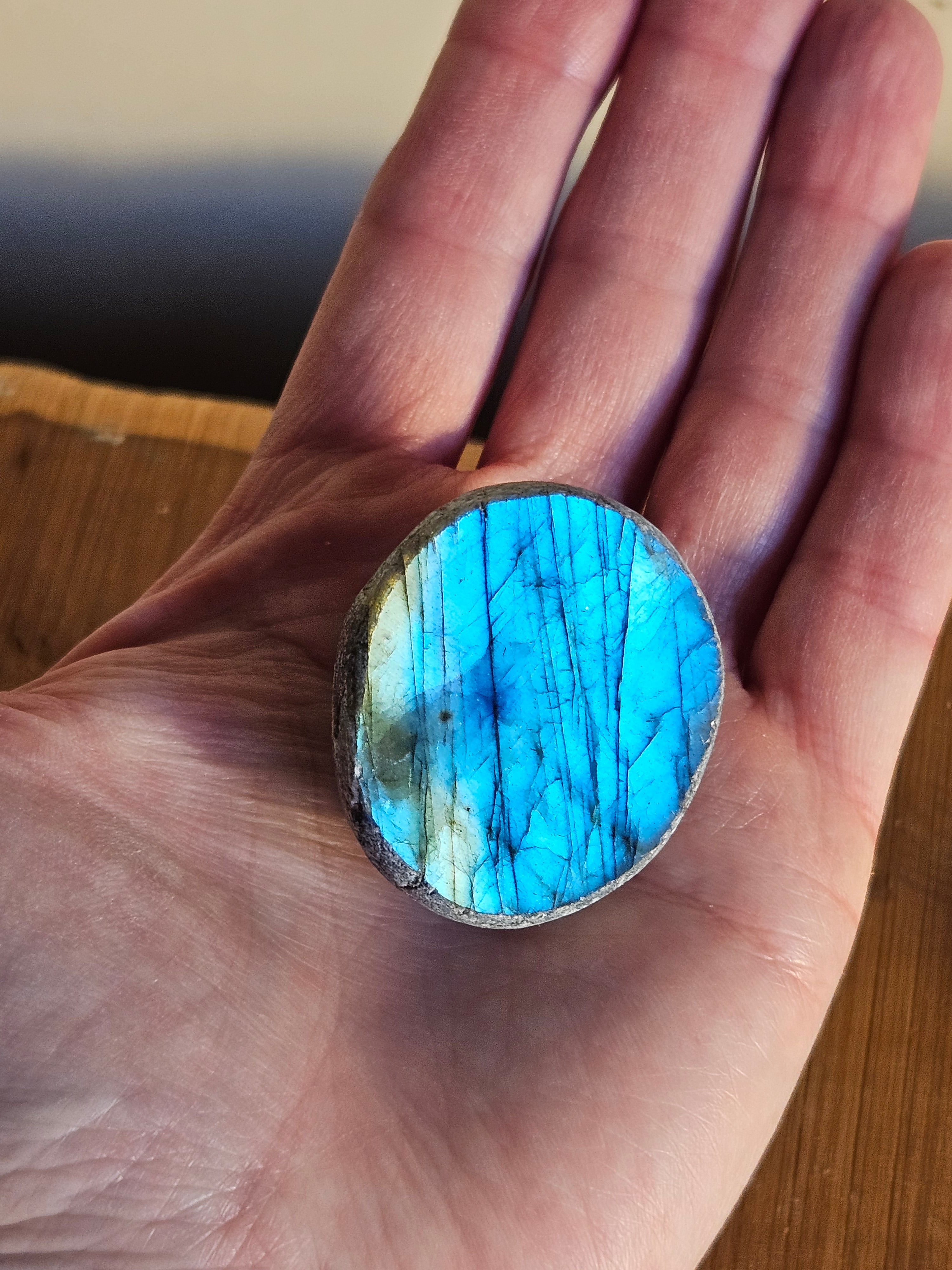 Hand holding a Labradorite dragon egg to show the size