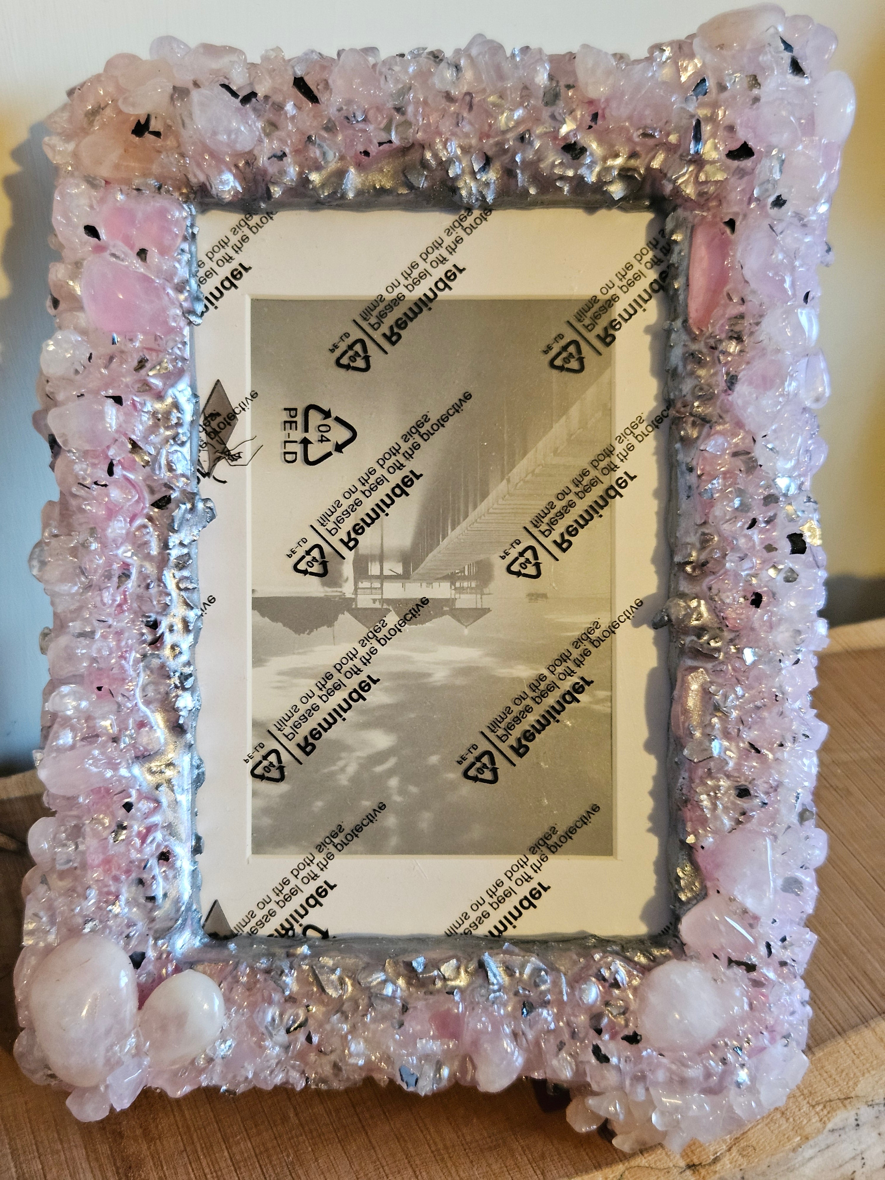 Decorative photo frame with pink Rose Quartz on a wooden surface