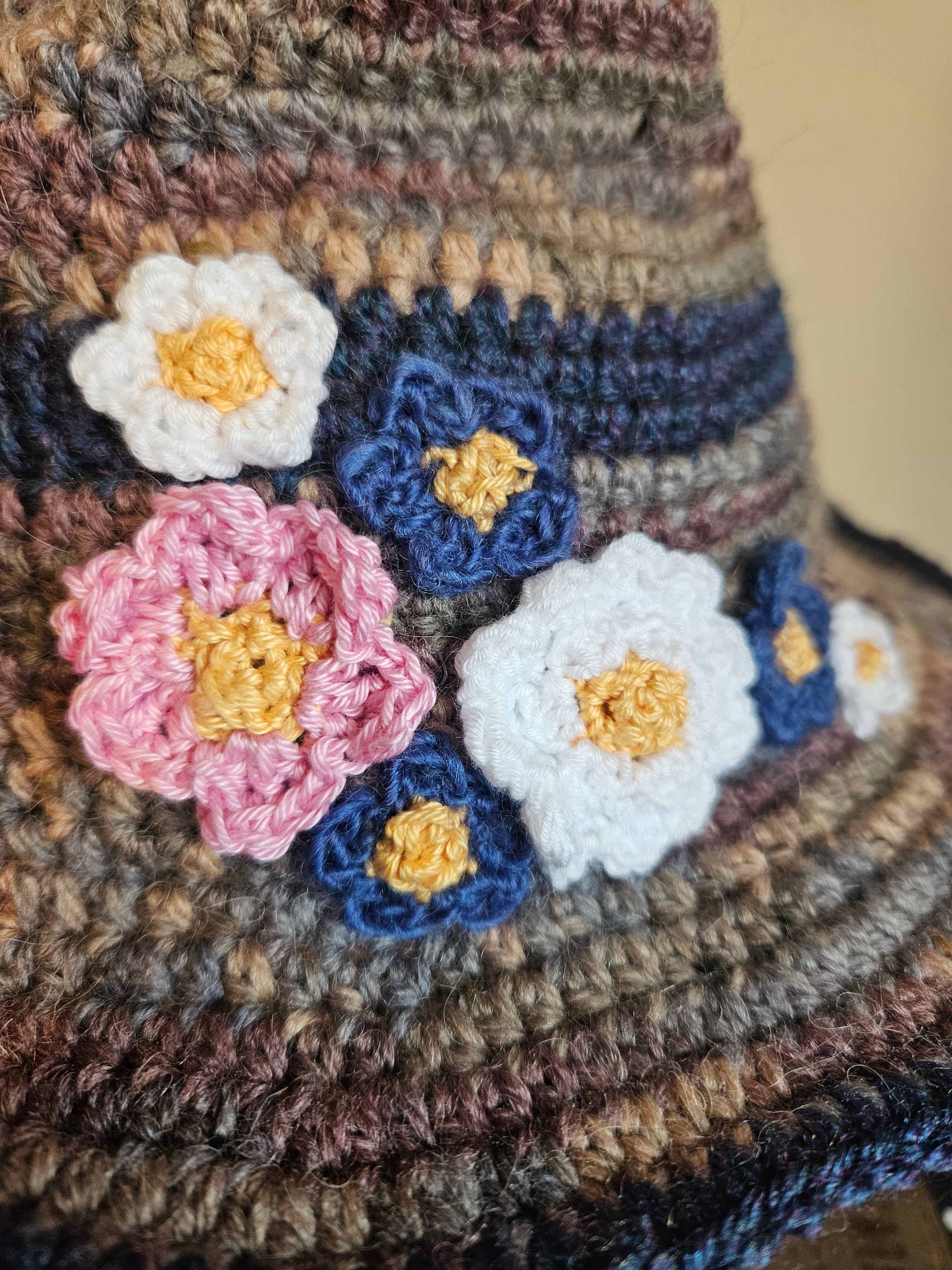 Close-up of a textured fabric with crocheted flowers in blue, white, and pink.