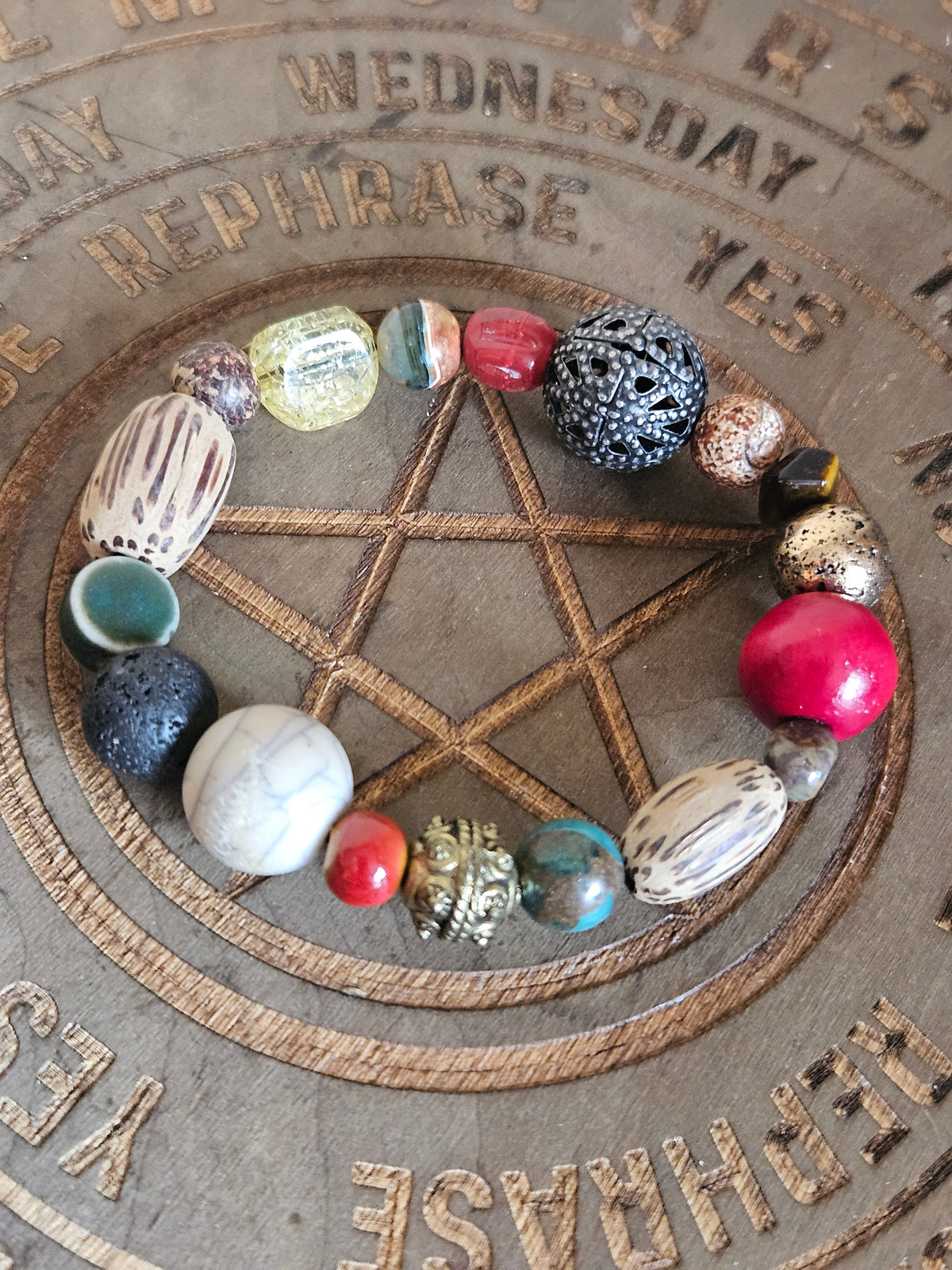 Beaded boho bracelet made from mixture of beads. On a wooden board showing a pentagram