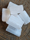 Five white selenite crystal chunks arranged on a round bronze-toned metal plate with engraved days of the week.