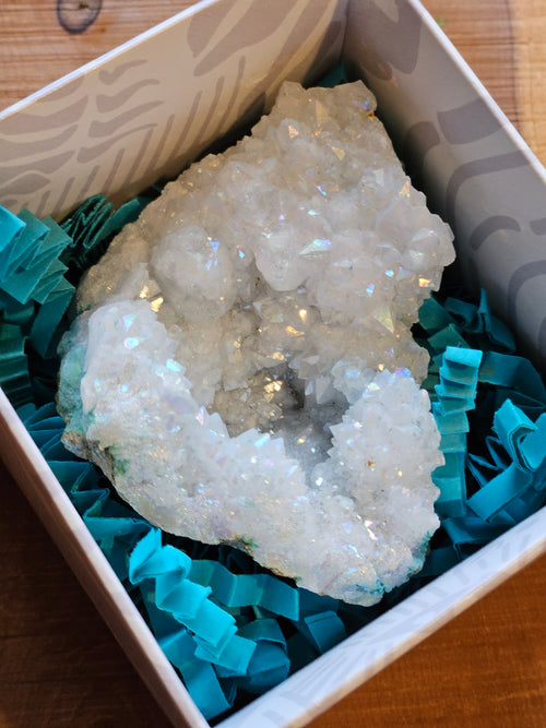 Crystal geode in a box with teal ribbons on a wooden surface