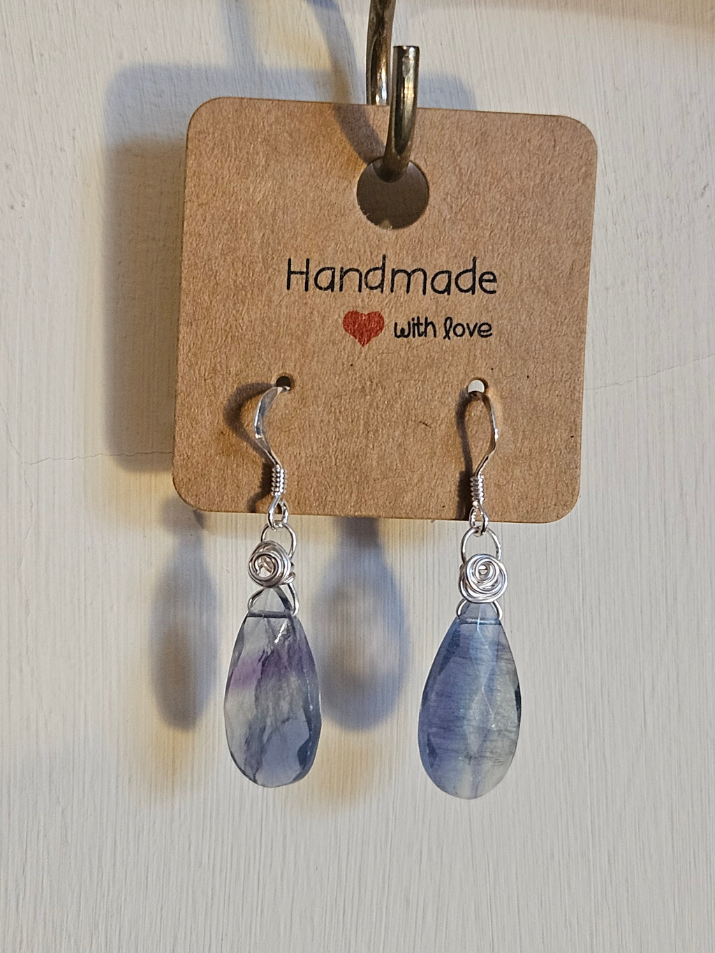 Teardrop-shaped earrings on a 'Handmade with Love' card against a light background