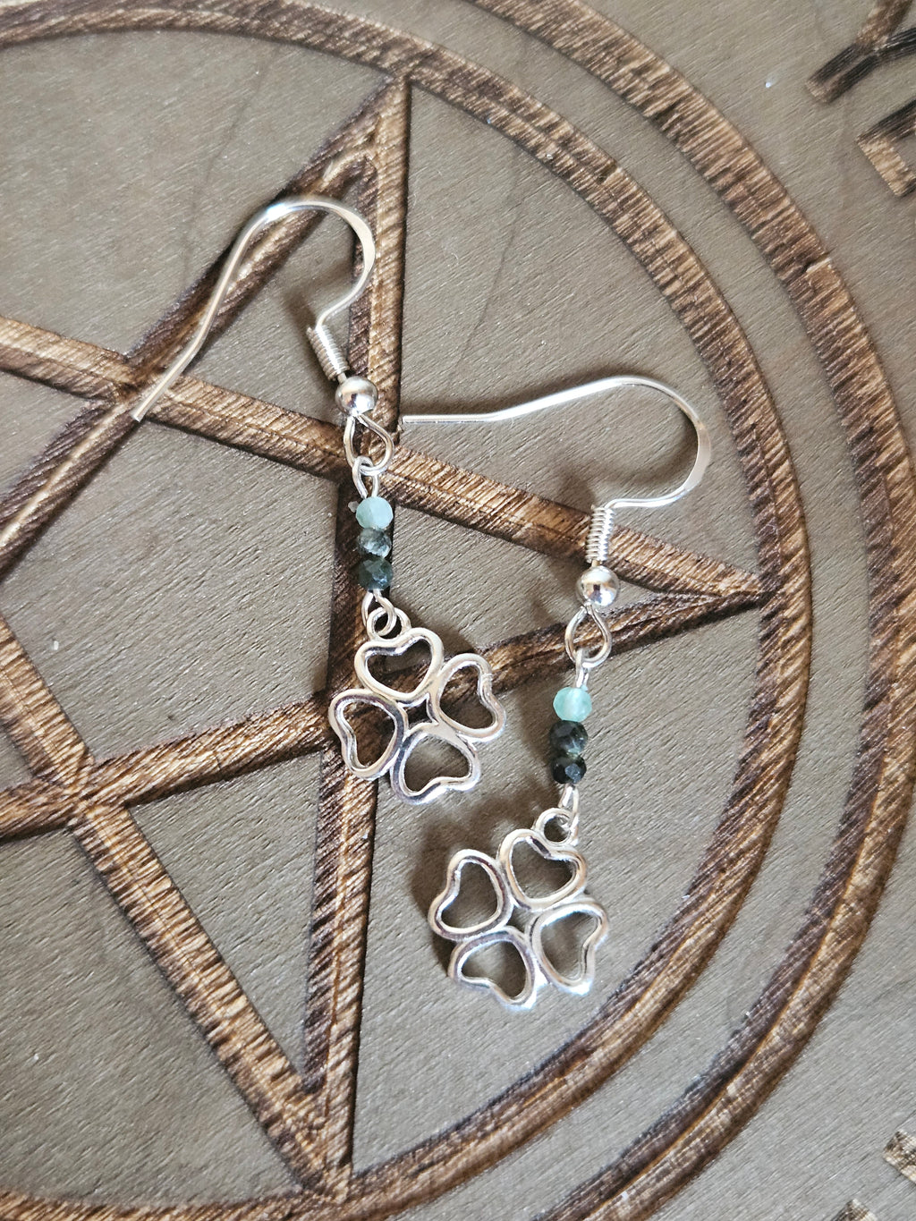 Silver 4 leaf clover earrings on a pentagram design background