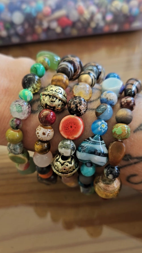 Stack of colorful beaded bracelets on a wrist with a blurred background
