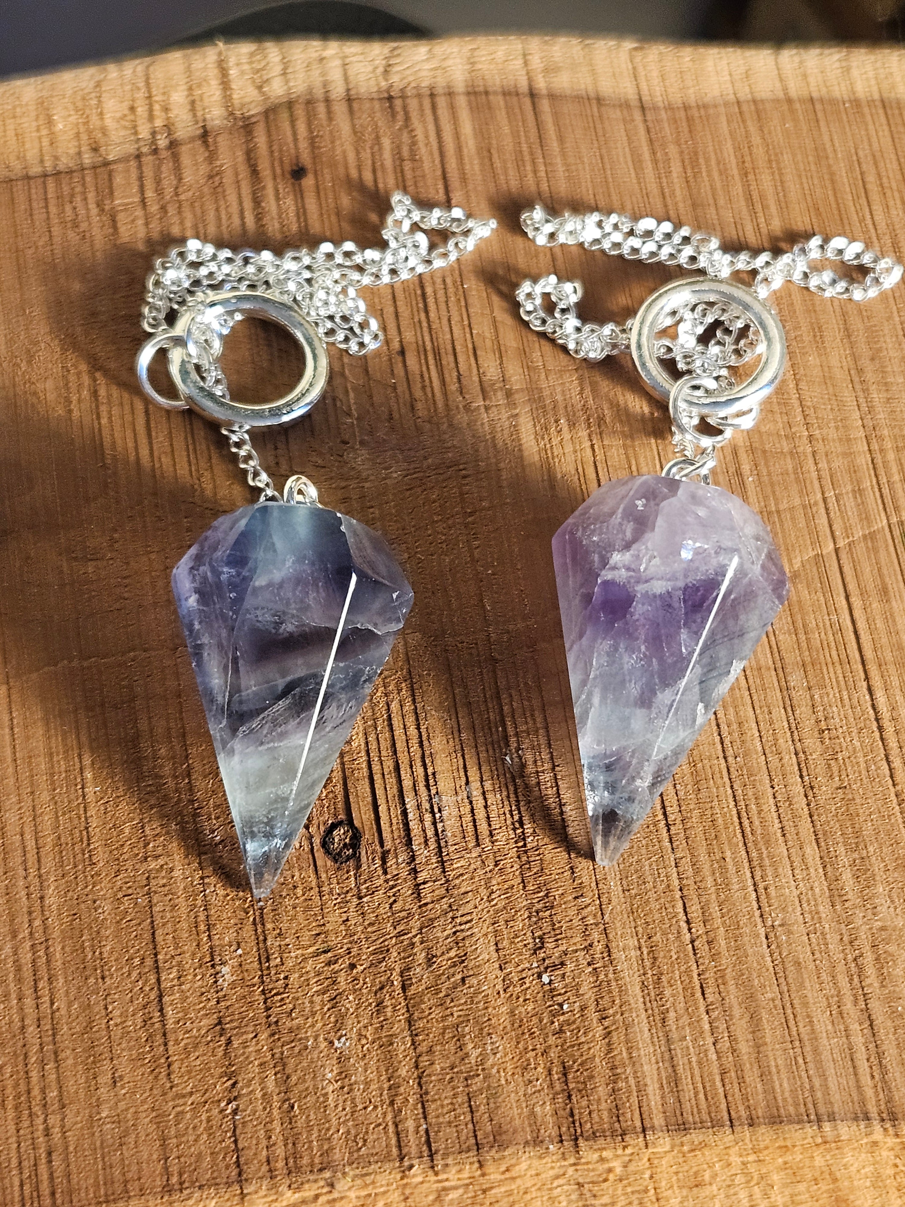 Two Fluorite pendulums on a wooden board
