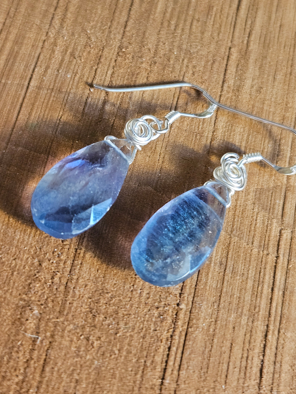 Blue teardrop earrings on a wooden surface