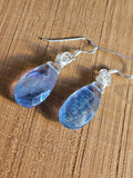 Blue teardrop earrings on a wooden surface