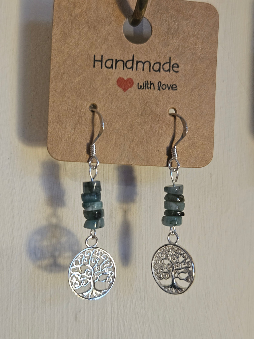 Pair of earrings with tree-of-life charms on a 'handmade with love' card.