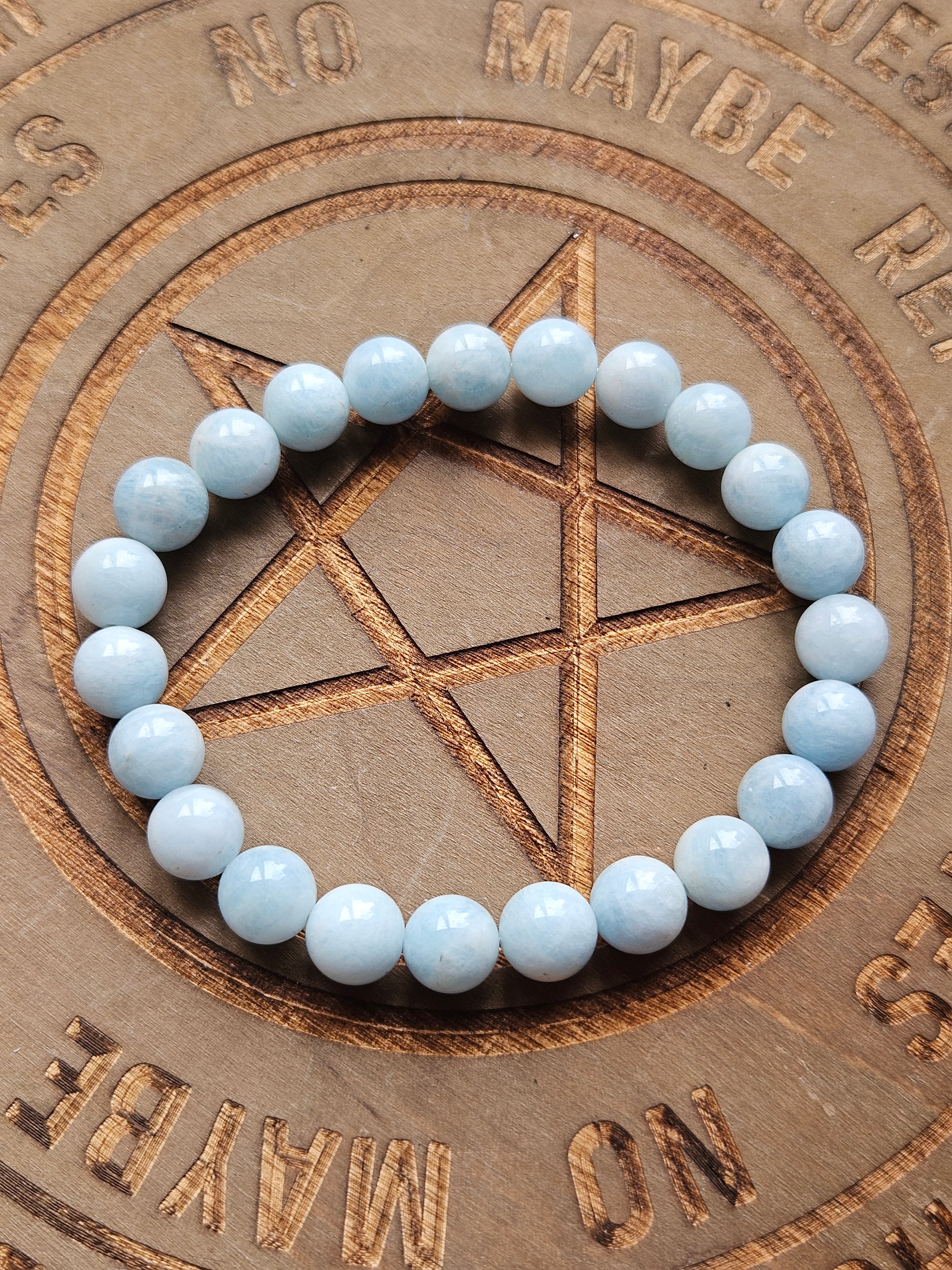 Light blue green beaded bracelet on a wooden board with pentagram